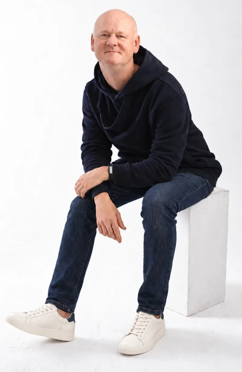 Mark Gossage seated in a navy hoodie and jeans